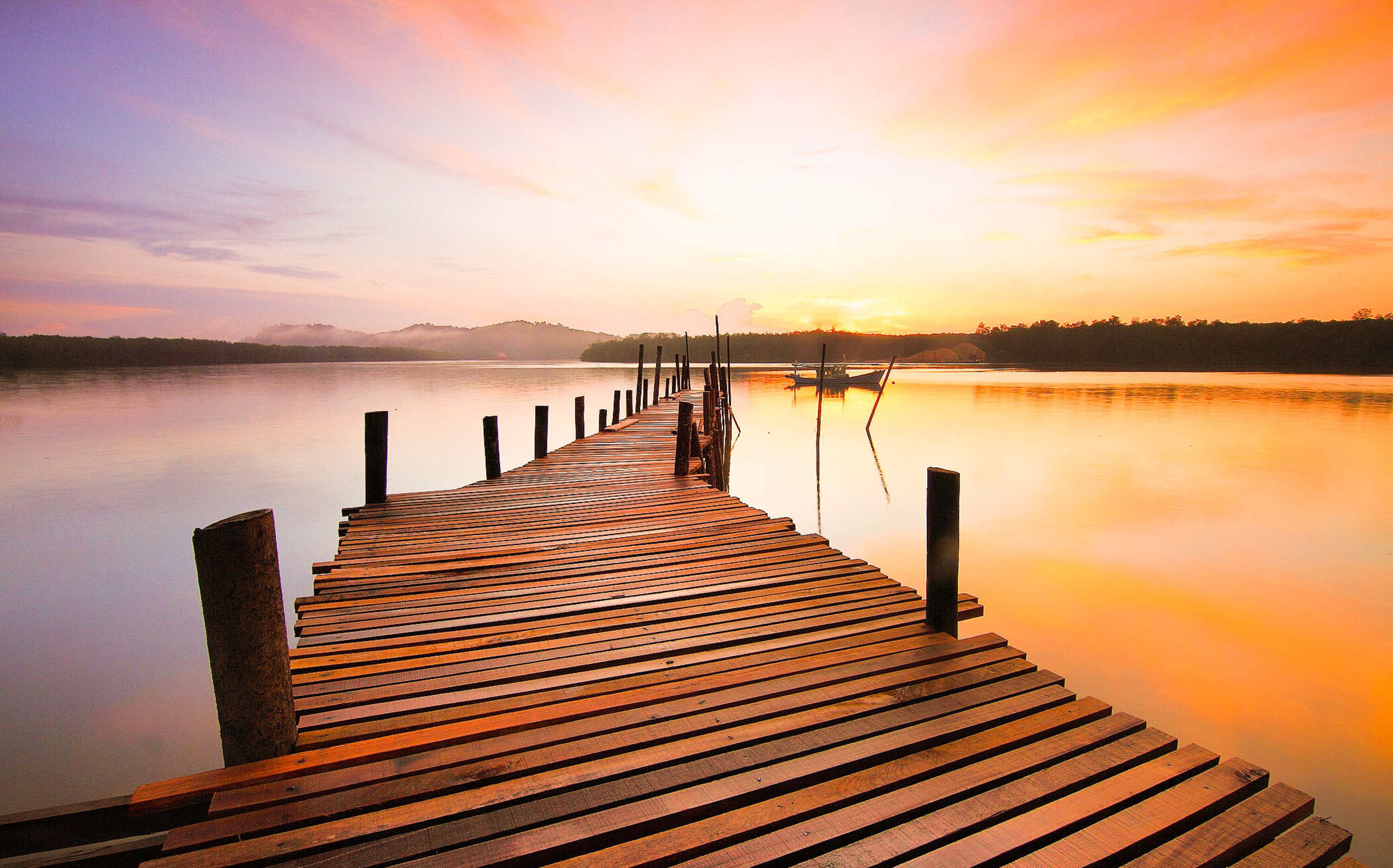 Foto zeigt Holzsteg in einen See in der Abenddämmerung.